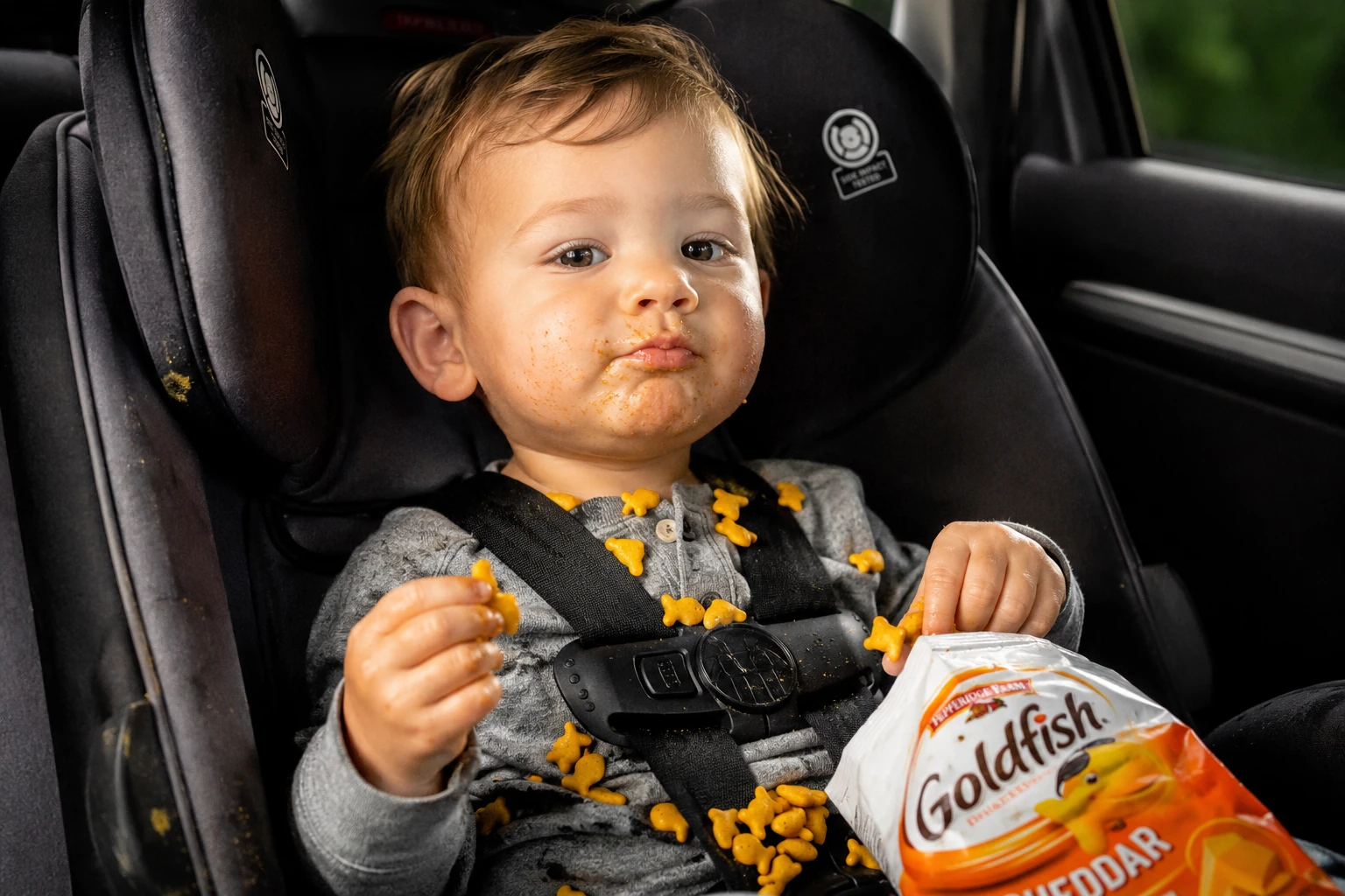 Child in car seat with a bag of Goldfish crackers