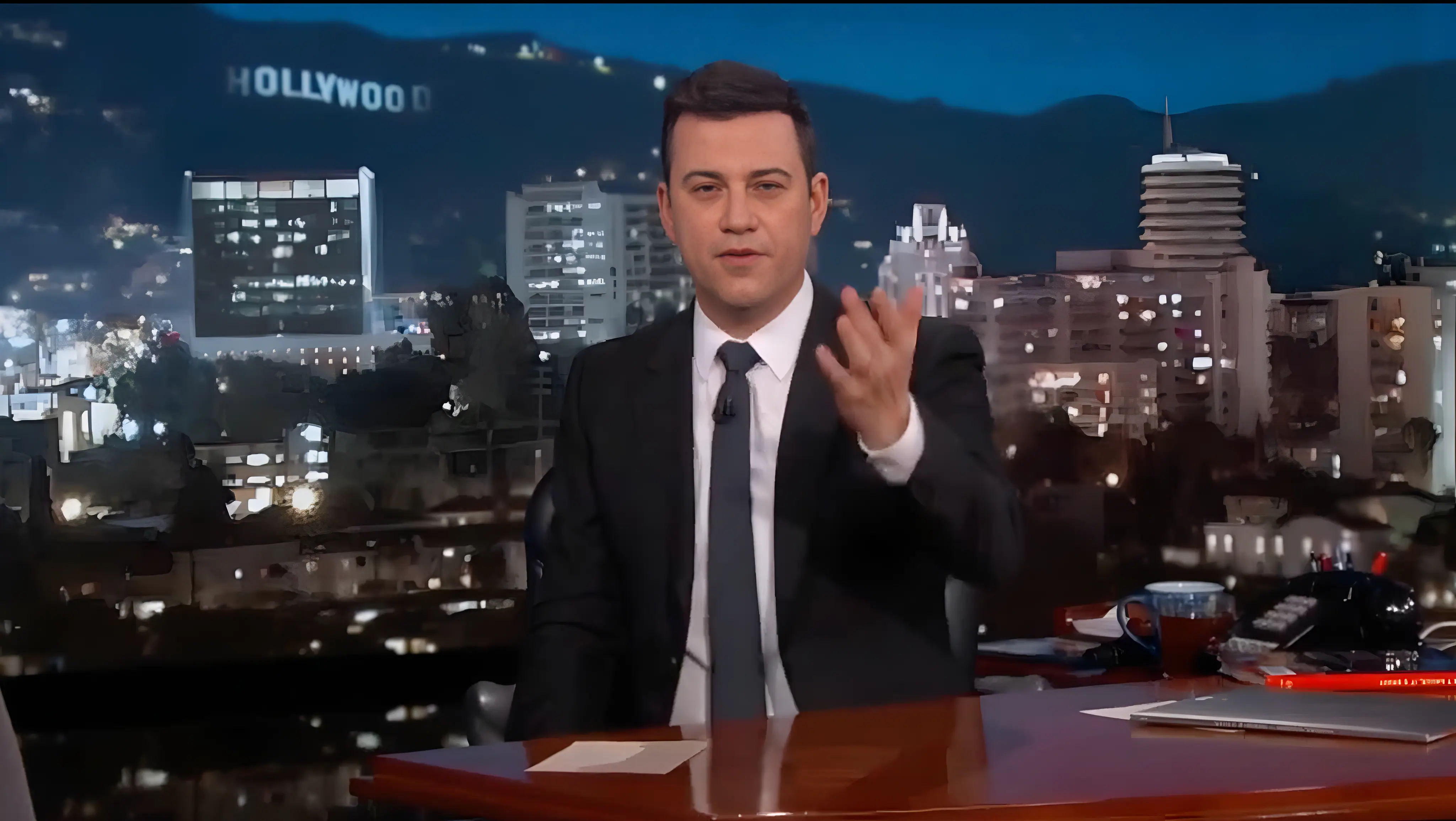 Jimmy Kimmel at his desk during the Machine 11 segment, Hollywood sign visible in background